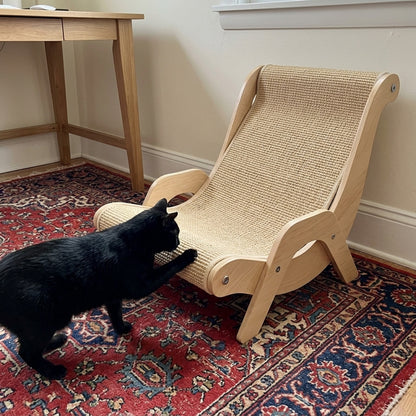 Black cat scratching the sisal edge of the lounger