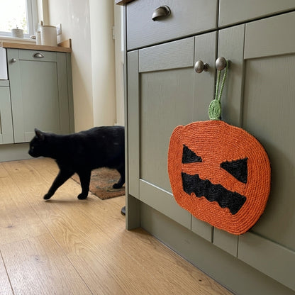 Halloween sisal scratcher, Pumpkin hanging on a kitchen cabinet with a black cat walking by